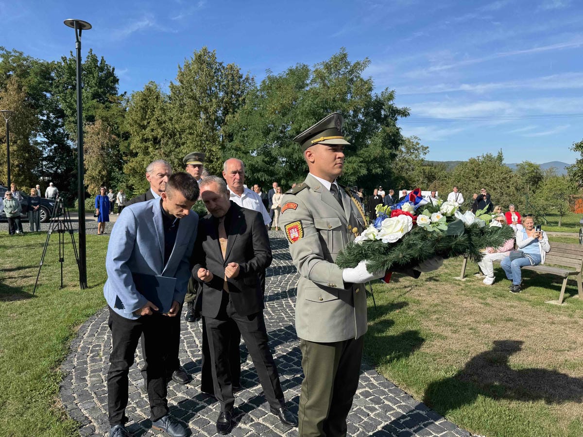 v popredí vojak s vencom v ruke a za ním zástup ľudí pred pietnym aktom Image
